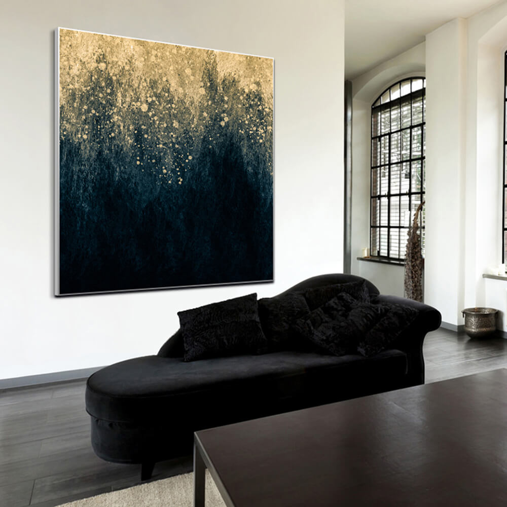 Quadratisches Akustikbild eines abstrakten Goldregens auf schwarzem Grund. Hängt an einer weißen wand hinter einem Sofa