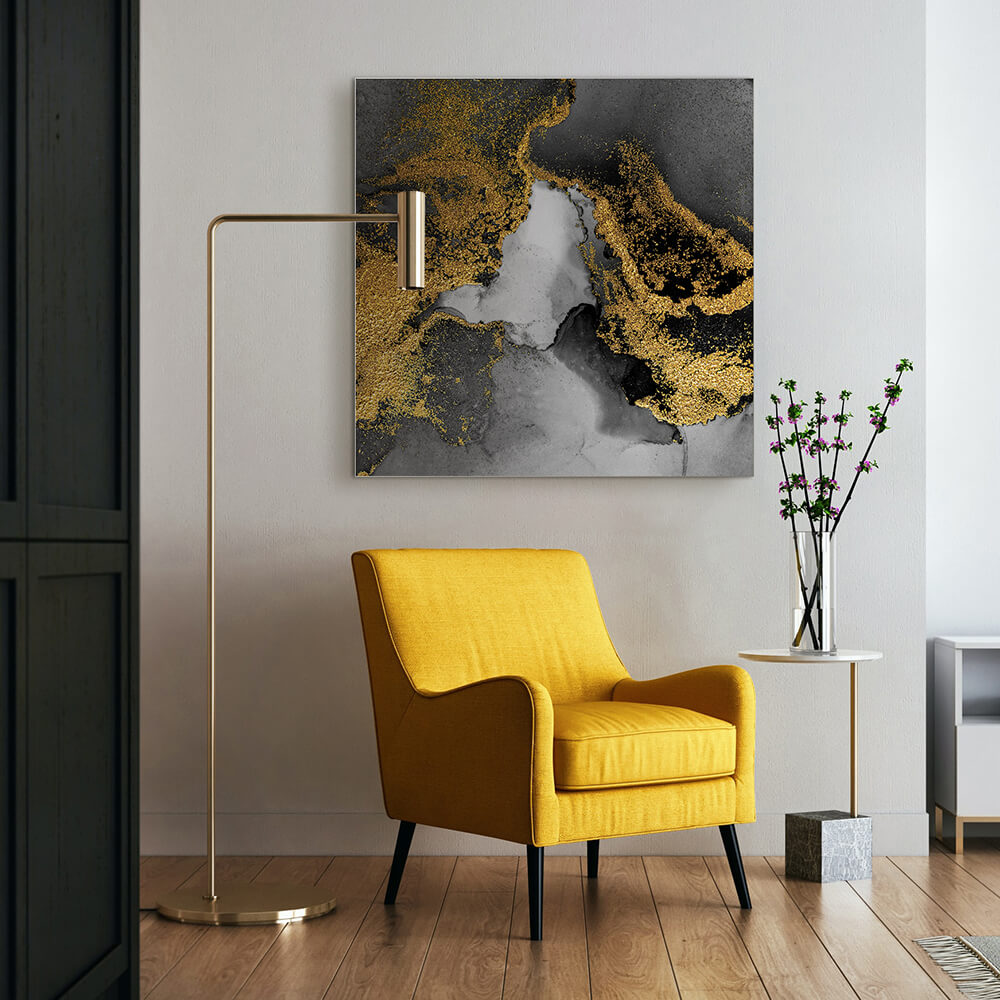 Quadratisches Akustikbild mit goldenen Akzenten auf grauem Grund, hinter einem gelben Sessel