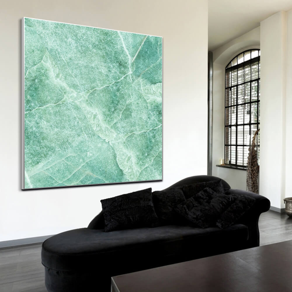 Quadratisches Akustikbild in grüner Marmoroptik hinter einem schwarzen Sofa