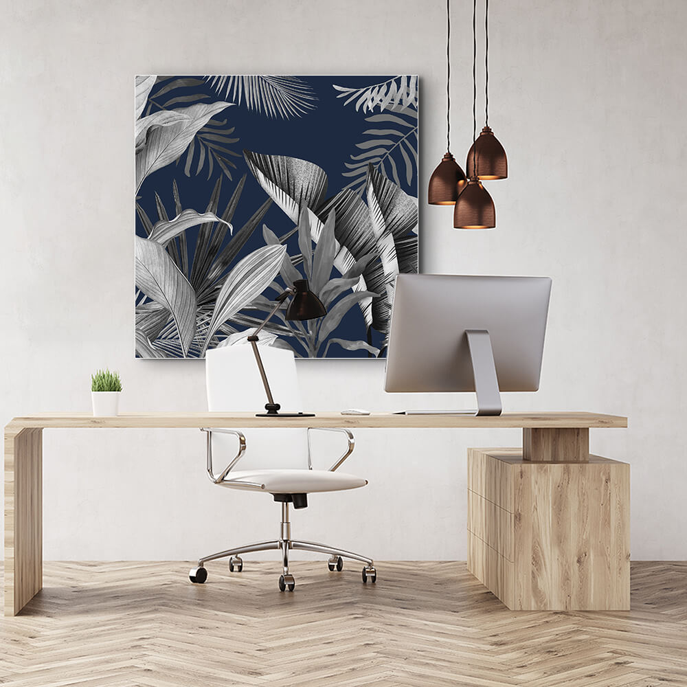 Quadratisches Akustikbild weißer und grauer tropischer Blätter auf dunkelblauem Grund, hinter einem Schreibtisch