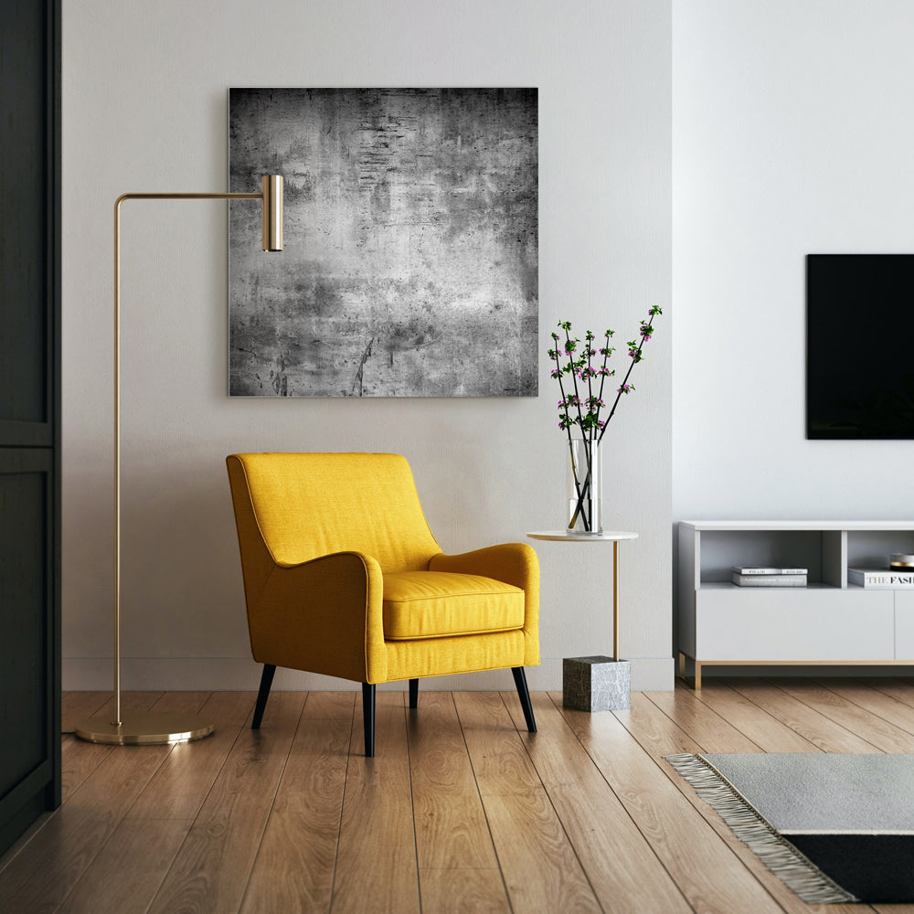 Quadratisches Akustikbild in grauer Betonoptik in einem Wohnraum über einem gelben Sessel